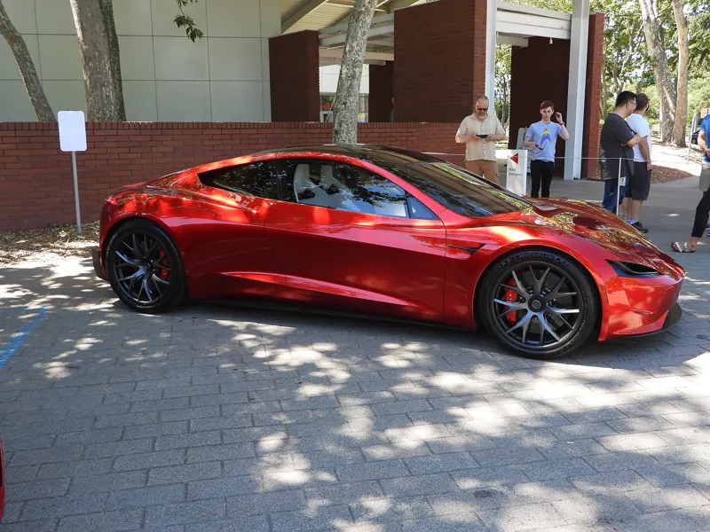 Red Roadster prototype parked outdoors on a paved plaza, seen from the side